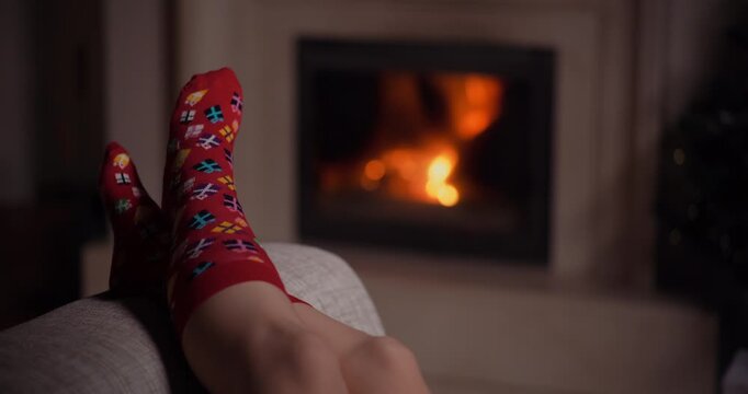 Relaxed feet in patterned socks by a glowing fireplace