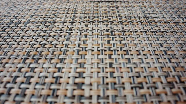 A detailed macro shot of a woven material reveals an intricate pattern of interlaced fibers in neutral tones