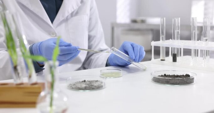 Laboratory testing. Scientist taking sample of sand at white table indoors, closeup