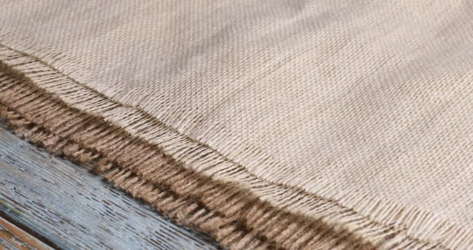 Woman putting folded burlap fabrics onto wooden table, closeup