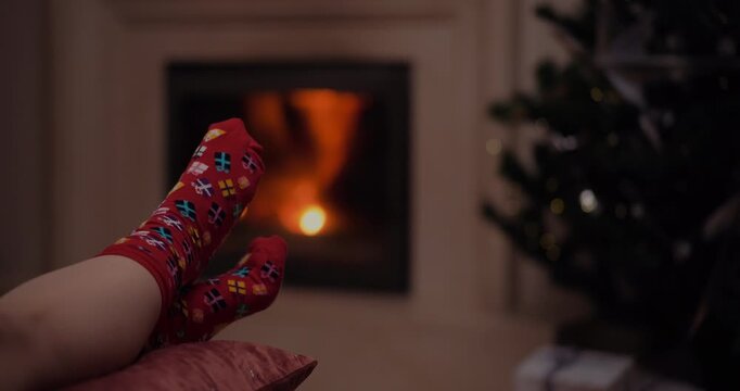 Feet in holiday socks by a glowing fireplace at Christmas