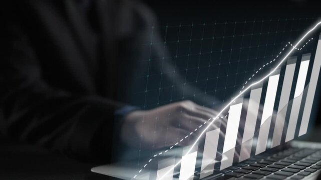 A professional businessman operates a laptop with visual graphs showcasing growth trends, representing the synergy of technology and financial analysis in a modern workspace. Copula
