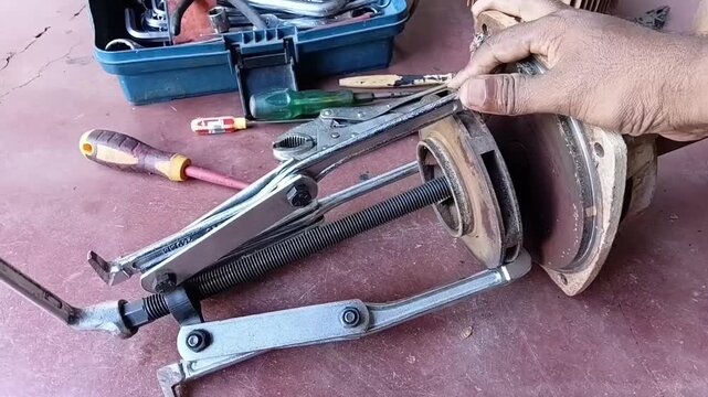 A mechanic uses a 3-jaw bearing puller to safely extract a tightly stuck impeller from the rotor shaft of a water pump.