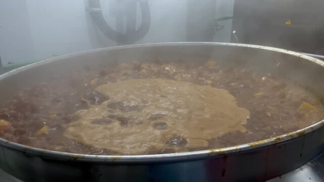 Beef being slowly braised in a steam-heated industrial kettle during food manufacturing operations. Large-scale cooking process used to develop flavor, improve texture, and support ready meal producti