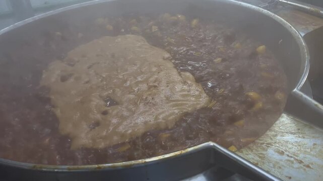 Beef being slowly braised in a steam-heated industrial kettle during food manufacturing operations. Large-scale cooking process used to develop flavor, improve texture, and support ready meal producti