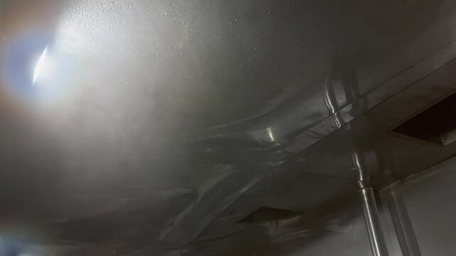 Steam generated from industrial cooking operations rising toward an exhaust hood and forming condensation droplets. Example of moisture management, ventilation systems, and environmental conditions in