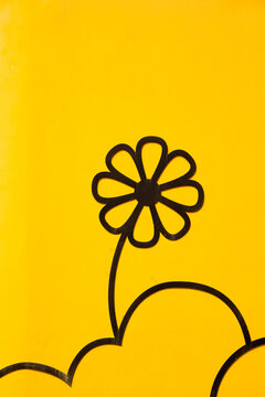 Black flowers painted on a yellow wall