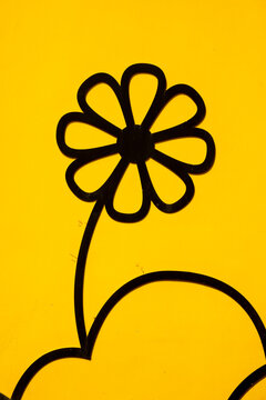 Black flowers painted on a yellow wall