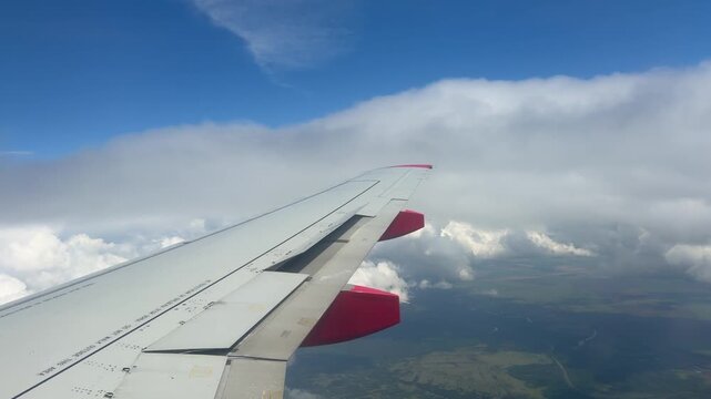 Above the Clouds: A view from an airplane window shows the wing soaring through a vast expanse of sky, with fluffy clouds and distant landforms below.
