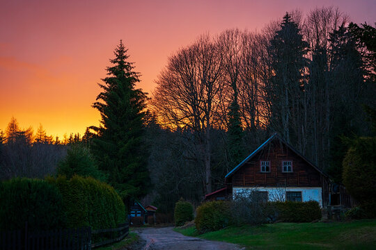 Rural cabin at sunset with colorful sky and forest