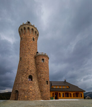 Stone observation tower and building against cloudy sky