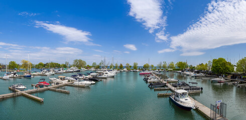 Naklejka premium A scenic wide angle view of numerous leisure boats, yachts, and motorboats moored at the docks of Scarborough Bluffs Marina under a bright blue sky on Lake Ontario in Toronto Canada