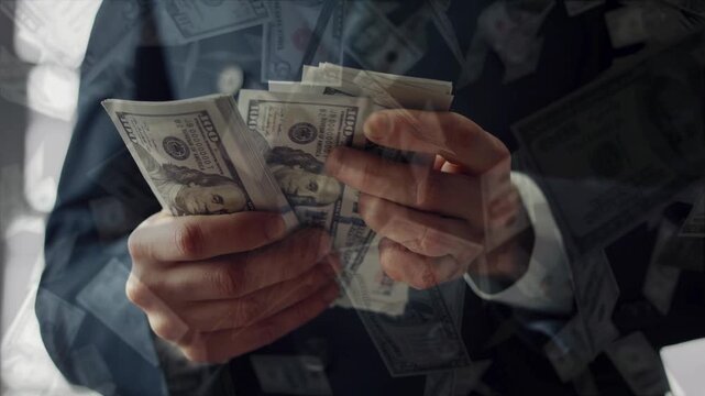 Businessman hands counting a large stack of US 100 dollar bills, with an animated overlay of multiple US dollar bills raining down around him. Wealth concept.