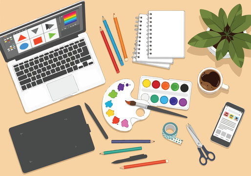 A creative workspace with laptop, art supplies, coffee