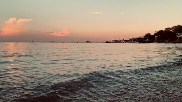 4K sunset seascape at Tanjung Lesung Beach, Banten, Indonesia, with gentle rippling waves, colorful reflections, fishing boats, and a tranquil shoreline. Ideal for nature, wellness, tourism, and backg