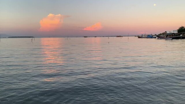 4K sunset seascape at Tanjung Lesung Beach, Banten, Indonesia, featuring calm water reflections, pastel clouds, moored fishing boats, and gentle rippling shoreline sounds. Ideal for nature, wellness, 