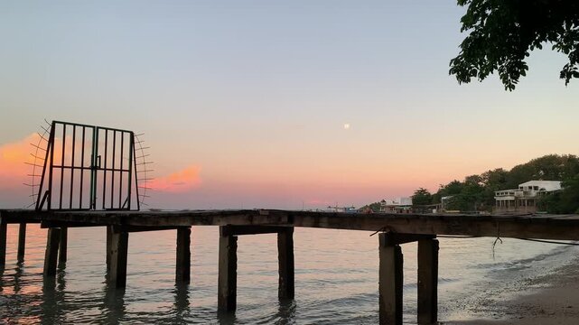 4K sunset view with a wooden pier and calm shoreline at Tanjung Lesung Beach, Banten, Indonesia. Gentle waves can be heard along the beach, ideal for travel, relaxation and nature themes.