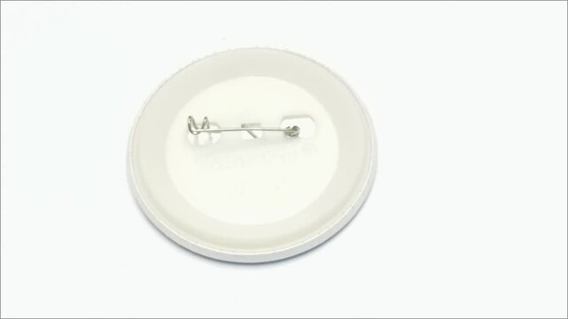 Plastic backing of a round pin button badge with metal safety pin clasp on clean isolated background.