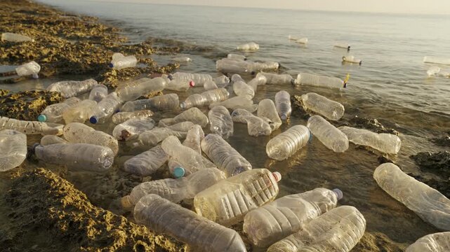 Plastic bottles floating in polluted sea along rocky shores in indonesia, southeast asia, ocean water pollution, single-use