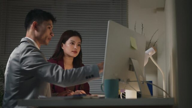 Stressed Asian Business Woman Rubbing Eyes While Working Late Night at Office with Male Colleague