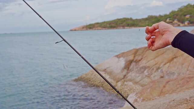 Close Up First Person View of Fishing Sinker Hanging on Transparent Line Near Tropical Rocky Coast, Saltwater Fishing and Marine Recreation