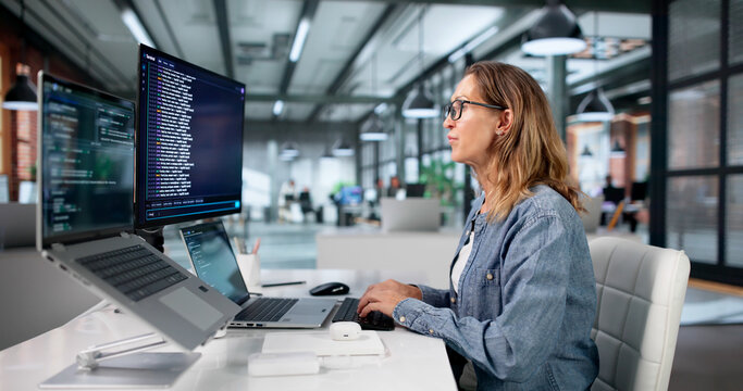 Mature Woman Coding Software On Laptop
