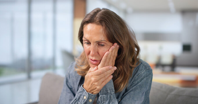 Woman Holds Her Cheek In Pain, Seeking Relief