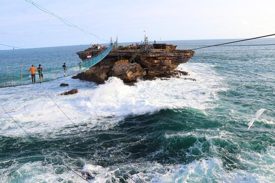 Timang beach rocky island with powerful ocean waves and traditional manual cable car ropes in Yogyakarta.