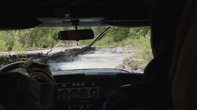 POV from inside an off-road vehicle approaching a rough river ford with logs and rocks in Aktur Valley, Altai Mountains, Russia, adventure travel and 4x4 expedition