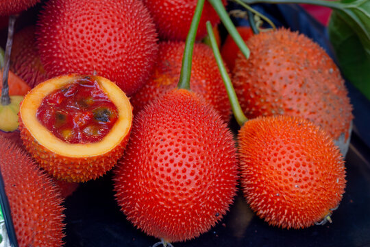 Fresh sweet gourd or gac fruit with bright orange-red spiky skin.