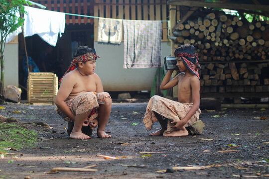 Two Asian boys from rural Indonesia happily listening to a vintage transistor radio in their traditional village