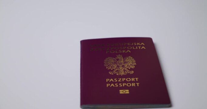Red  Polish passport lying flat on a clean white surface under soft, diffused lighting, jib shot