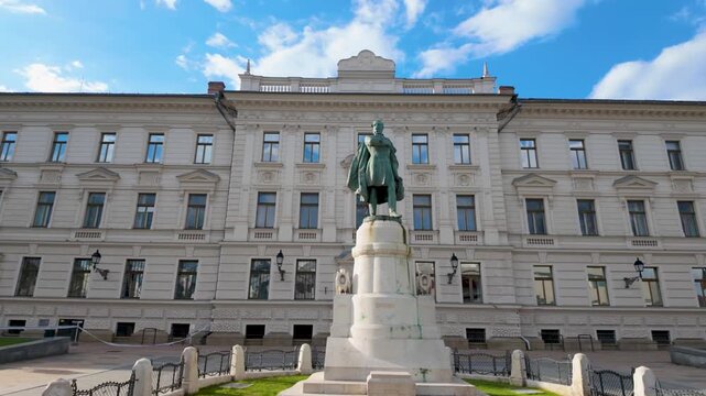 P&eacute;cs, Hungary &ndash; May 1, 2026: Statue monument standing before a historic public building in downtown P&eacute;cs