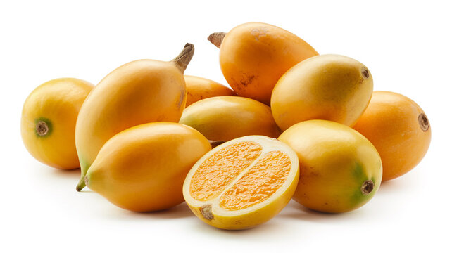 Pile of ripe yellow babaco fruit with one cut in half revealing juicy orange pulp