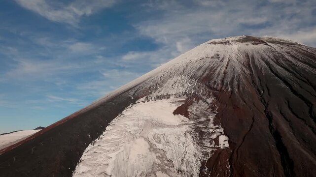Drone footage of Avachinsky Volcano with snow-covered crater and dark volcanic ash slopes under blue sky, Kamchatka Krai, Russia, remote wilderness landscape