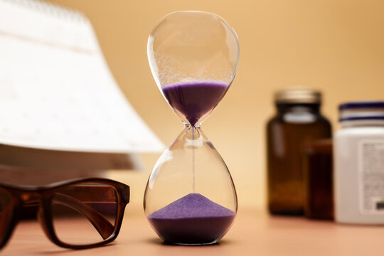 Hourglass with medicine bottle, reading glasses and calendar,aging society, senior healthcare