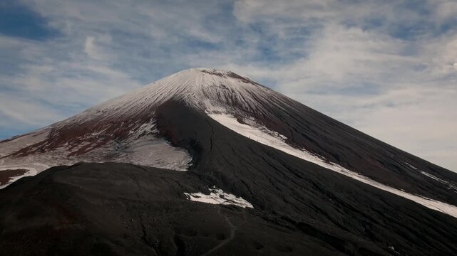 Footage of Avachinsky Volcano with snow patches on black volcanic ash slopes under a cloudy sky in Kamchatka Krai, Russia, dramatic wilderness landscape