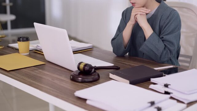 Asian woman lawyer working on legal case with laptop computer and gavel documents in home office preparing court trial consultation professional attorney