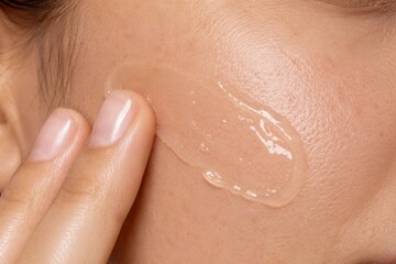 Fototapeta premium Close Up Portrait of Applying Clear Facial Gel to Cheek During Skincare Routine