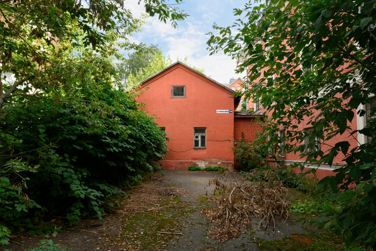 A courtyard between red brick houses in Kostroma, Russia. The inscription on the sign: 'Nizhnyaya Debra Street'
