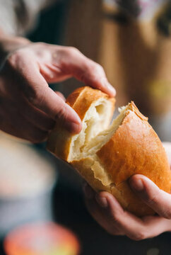 Close-up of hands breaking bread, warm tones, sensory food experience, soft light