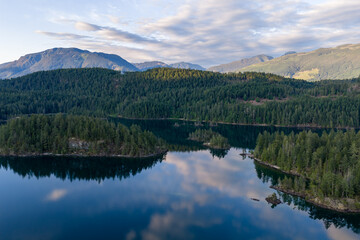 Obraz premium Calm Mountain Lake Reflection Over Dense Evergreen Forests at Harrison Lake, BC, Canada