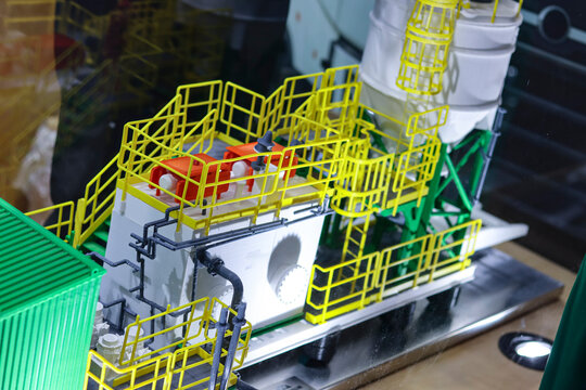 3D-printed industrial equipment model with yellow railings and pipes