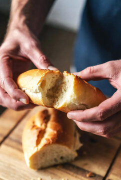 Close-up of hands breaking bread, warm tones, sensory food experience, soft light