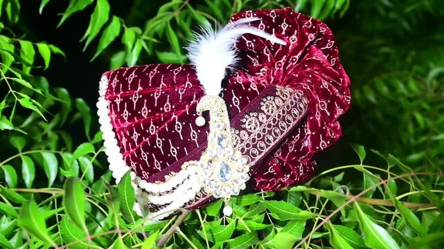 Close-up footage of a traditional Indian groom wedding turban (Safa or Pagdi) decorated with an ornamental brooch, gemstones, and white feather. The ceremonial headwear is an essential part of groom.