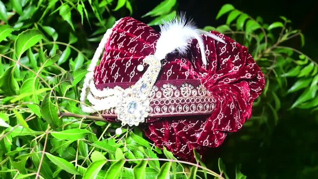 Close-up footage of a traditional Indian groom wedding turban (Safa or Pagdi) decorated with an ornamental brooch, gemstones, and white feather. The ceremonial headwear is an essential part of groom.
