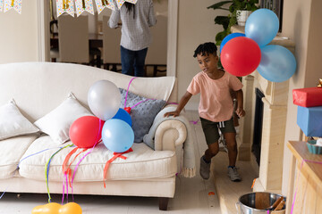 Obraz premium Family parent and child celebrating in living room with balloons on beige sofa, copy space