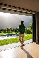 Naklejka premium Sun rays are streaming through sliding glass door onto wood floor while pool is reflecting hills