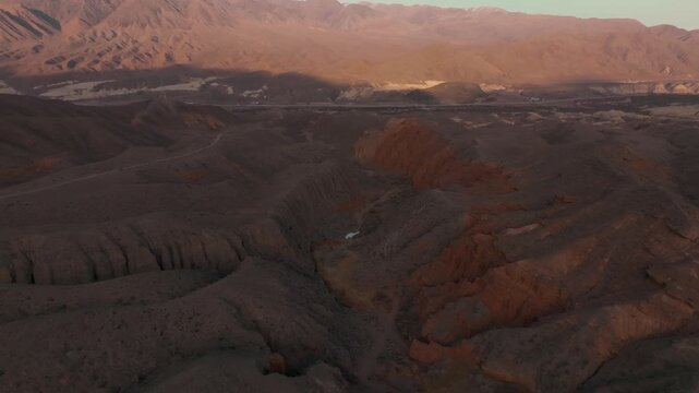 Drone footage of rugged Kok-Moynok Canyon with eroded ridges and dry riverbed in warm evening light, scenic landscape in Issyk-Kul Region, Kyrgyzstan