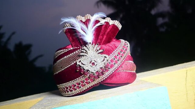 Close-up footage of a traditional Indian groom wedding turban (Safa or Pagdi) decorated with an ornamental brooch, gemstones, and white feather. The ceremonial headwear is an essential part of groom.